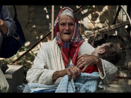 An elderly woman holds a disabled relative as they are evacuated from a flooded neighbourhood in Kherson, Ukraine, yesterday.