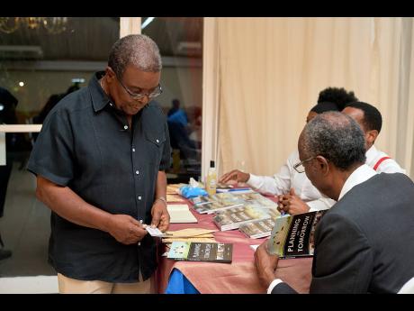 Mortimer Thompson (left), has his  copy of ‘Planning for Tomorrow’ signed by 
Dr Ashwell E. Thomas. CONTRIBUTED PHOTOS
