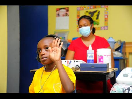 Marvesha Goodgame-Chin (right), certified occupational hearing conservationist, Jamaica Association for the Deaf, conducts a hearing exam on Elijah James at the Kiwanis Club of New Kingston Children’s Health Screenings at Liguanea Prep School in St Andre