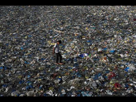 A boy walks on the plastic waste at the Badhwar Park beach on the Arabian Sea coast in Mumbai, India.