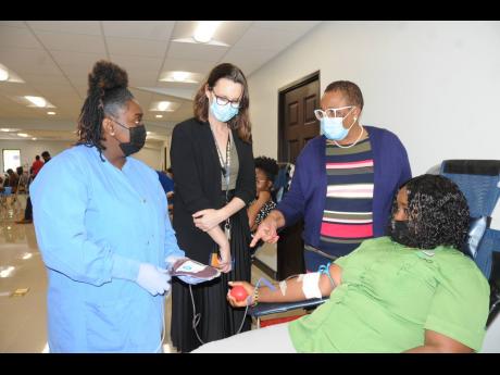 National Blood Transfusion Service representative Tanika Dewar-Taffe (left) explains the blood donation process to Musson Foundation Chairperson Melanie Subratie (second left); General Accident Insurance Company (GenAc) CEO Sharon Donaldson (second right),