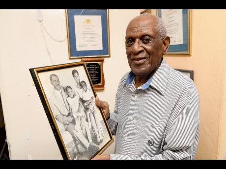 Gleaner subscriber and centenarian Norman Jarrett shows a photo of himself, wife Cecile and their children