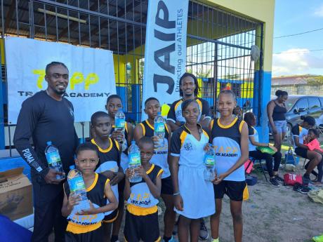 Tyquendo Tracey (left) and Mattheu Tapper (second right), founder of Tapp Track Academy, pose with children who are preparing for the JISA/Little Caesars Prep School Championships tomorrow.