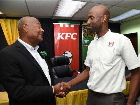 Jamaica Football Federation president, Michael Ricketts (left), shakes the hand of Restaurants of Jamaica Brand Manager, Andrei Roper, during a press conference at his organisation’s office yesterday.