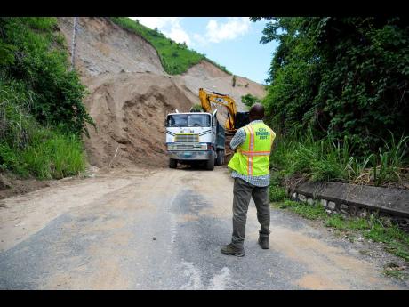 Dennis Hall from the City Engineering Department watches closely as workmen from KNN Construction clear Tavistock Terrace yesterday. The roadway was blocked after workmen cutting a road to enter a property encountered difficulties that caused a landslide.