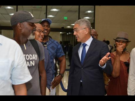 Richard Byles (centre), governor of the Bank of Jamaica (BOJ), speaking with customers at the Bank yesterday. The Bank of Jamaica officially started distributing the new banknotes to the public. These new notes will eventually replace the old banknotes cur
