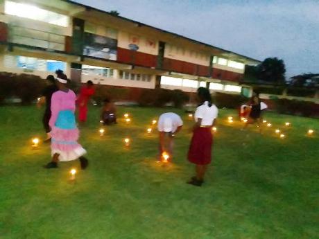 Mourners lighting candles on the lawn of the Green Island High School, at the caldlelight vigil for the school’s founding principal, the late Dr. Simon Clarke