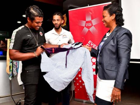 Akeem Tate (left), participant from the first cohort of Project STAR’s Employment Programme, examines one of the outfits contributed by Image Training Centre at the launch at Red Stripe Jamaica, recently. Looking on are ZJ Tomo, who was guest speaker at 