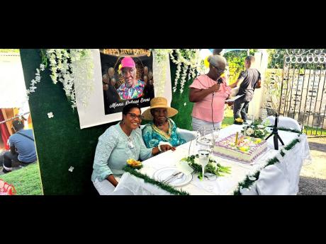 Centenarian Minna Delores Evans poses with her niece, Dian Evans, during a celebratory service to mark her 100th birthday. At right is Arlene Evans Douglas, sister of Dian Evans.