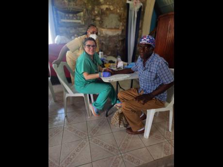 Alfred Graham (right) gets his blood pressure checked by an AOJAH medical staff inside the St George’s Anglican Church at Blackstonedge in St Ann.