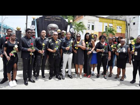 Mayor Delroy Williams (centre) and members of the Kingston and St Andrew Municipal Corporation (KSAMC) prepare to lay roses at the Secret Gardens Monument in downtown Kingston, during a wreath laying ceremony to commemorate yesterday’s National Day of Mo