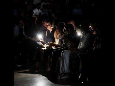 Mourners use light from their cellphones to read after a power outage during the thanksgiving service for the life of Captain Blake James Roper, at the National Indoor Sports Centre yesterday.