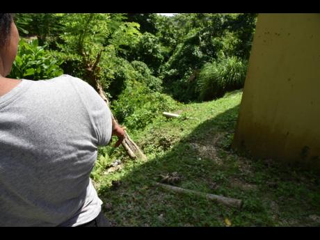 The rushing waters in a nearby ravine has gradually eroded the soil from the property occupied by 29-year-old Nicole Gooden and her family. She is hoping to get assistance to erect a retaining wall.