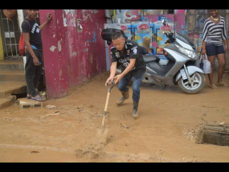 A business operator cleans muck from his establishment after sections of Montego Bay were flooded after heavy rainfall in November 2017.