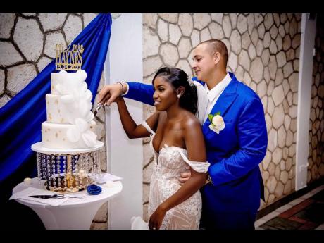 The newly married couple engage in the traditional cutting of the wedding cake, made with love by Mecheeka Johnson of Sweets Boss Ja.