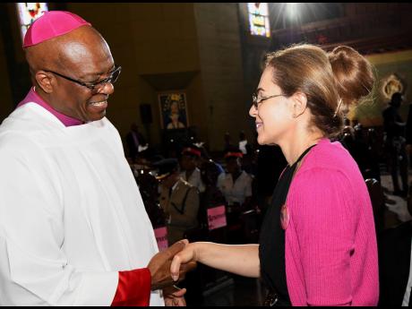 Reverend Kenneth Richards, the Roman Catholic Archbishop of Kingston, greets Dr. Eileen Chin, widow of Lascelles Chin, at his service of thanksgiving at the Cathedral of The Most Holy Trinity in Kingston last Wednesday.