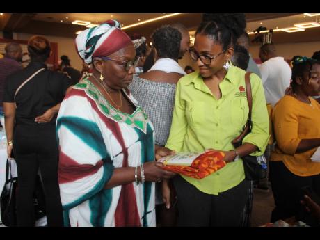 Amsale Maryam (left), of the Ethiopian Orthodox Church Batik Group talking with a patron at Christmas in July on Wednesday, July 12, about a piece of batik tie-and-dye printed by a member of the group. 