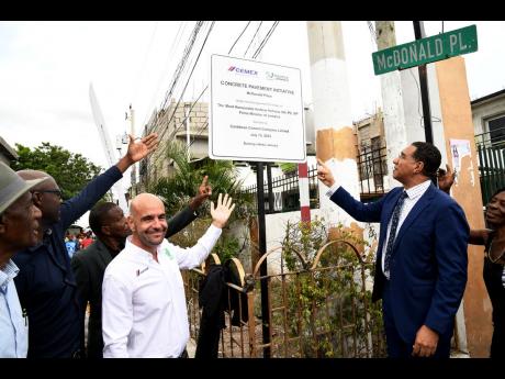 Managing director of Caribbean Cement Company Limited (fourth left) and Prime Minister Andrew Holness (right) participate in the symbolic unveiling of signage following a ceremony to commission a concrete pavement in the prime minister’s St Andrew West C