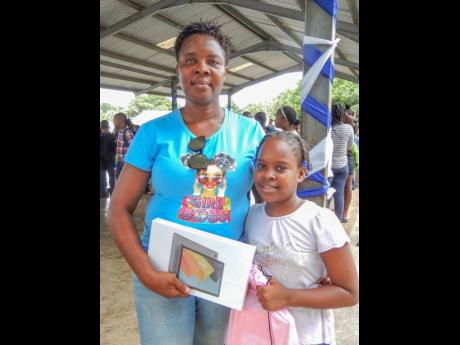 Grade Three top-achiever at Exchange All-Age School, Tessanne Cobourne, and her mother, Veron Daley-Cobourne, with a tablet she received from Ian Clough. 