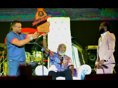 Red Stripe Brand Manager Nathan Nelms (left) presented the Living Legend Award to veteran crooner Freddie McGregor, as his son, Daniel ‘Chino’ McGregor, looks on.