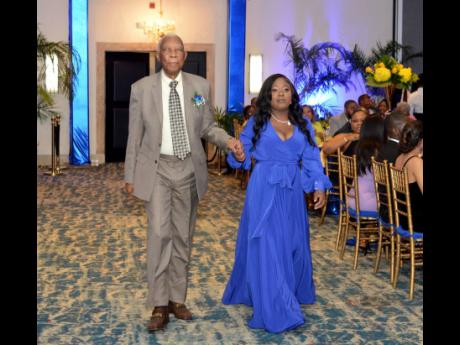 AJ Nicholson KC, who celebrates 50 years at the Bar, is escorted by Tamika Harris, an attorney-at-law from the JAMBAR Social Affairs Committee, to receive his award.