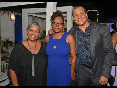 Cherice McIntosh is sandwiched by Valerie Virtue and Terrence Slater, business manager, GraceKennedy Limited.