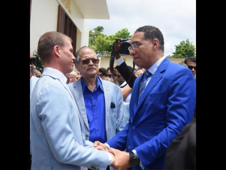 Prime Minister Andrew Holness expresses condolences to widower Adam Stewart as Robert Russell looks on.
