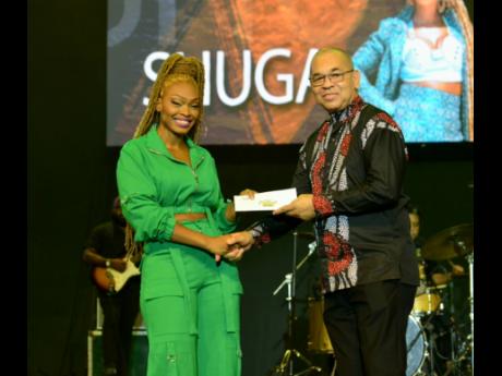 Orville Hill (right) presents the second-place prize in the National Festival Song Competition to Shuga at the National Arena on Saturday.