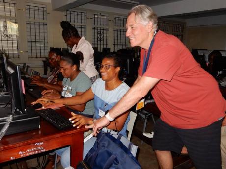 Brad Adams, founder and co-director of Teach the Teachers, assists teacher Opaline Burton on the computer during an IT training session at the Ocho Rios High School.