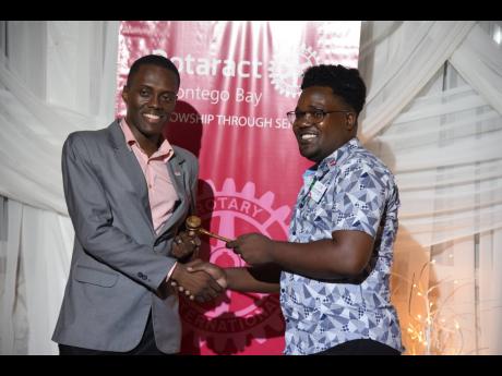 Gavin Anderson (left), president of the Rotaract Club of Montego Bay, accepting the gavel, the symbolic instrument of his office, from immediate past president Mario Campbell at the installation ceremony held at Day O’ Plantation Restaurant in St James. 