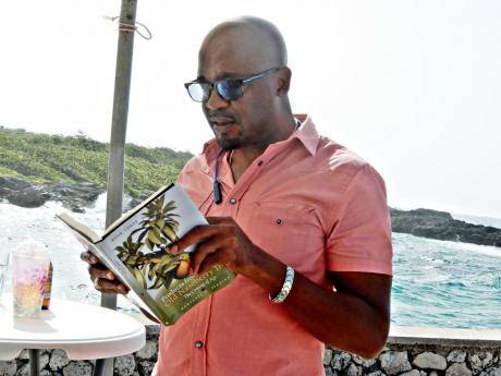 Otis Simpson, principal, Clarksonville All-Age School in St Ann, reads a section of Hortense M. Jenkins’ book, ‘Products from Under the Old Naseberry Tree’, during the book launch.