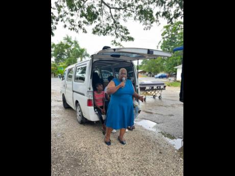 Senior teacher at the Green Island High School in Western Hanover and community activist, Shorna Miller, takes cover from the sun and drizzling rain, as she addresses participants in the peace march in Green Island.