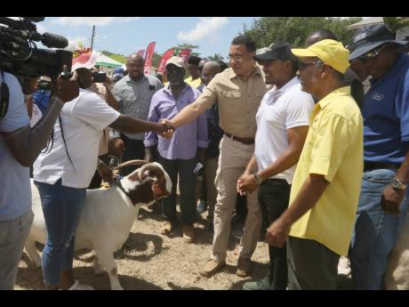 Prime Minister Andrew Holness greets a female farmer as Floyd Green (third from right) minister of agriculture, fisheries and mining, and Trevor Bernard (second from right) president of the Small Ruminants Association look on at the Denbigh Agricultural, I
