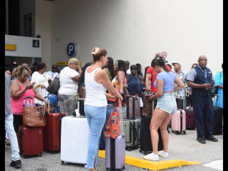 Passengers await transportation to leave the Sangster International Airport after their outgoing flights were cancelled on Thursday as a result of the closure of the runway.