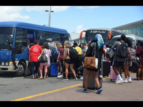 Several people boarding buses at the Norman Manley International Airport in Kingston to get to Montego Bay, St James, on Thursday after their flights were diverted from the Sangster International Airport because of runway expansion works under way.