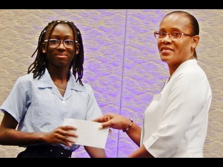 Ogette Pryce (left) of Exchange All-Age, who is heading to St Hilda’s High, collects her grant from Marie Mills, assistant financial controller at Moon Palace Resorts Jamaica, during Moon Palace Foundation’s annual PEP presentation and luncheon on Thur