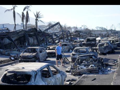 A man walks through wildfire wreckage on Friday, August 11, in Lahaina, Hawaii, in the United States.