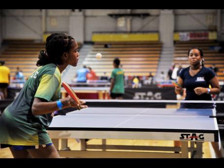 
St Catherine High School’s Keeara Whyte (left) serves to Kingston Table Tennis’ Karecia Peterkin during the National Junior and Senior Table Tennis Championships at the National Indoor Sports Centre, Independence Park Limited, on Friday.
