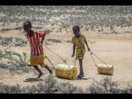Young girls pull containers of water as they return to their huts from a well in the village of Lomoputh in northern Kenya, in May 2022. 