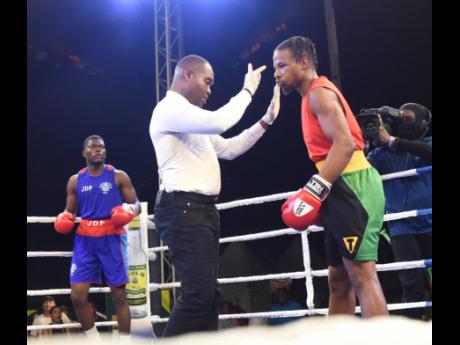 Referee Anthony Fuller (centre) administers the standing eight count to Malcolm Peck (right) from GC Foster College Gym after he was knocked down by Jerone Ennis (left) from the Jamaica Defence Force  Gym in their super middleweight clash at the Jamaica Bo
