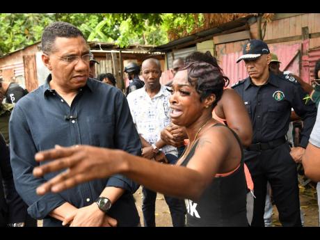 Prime Minister Andrew Holness (left) listens to an emotional Gregory Park resident as Police Commissioner Antony Anderson looks on during a tour of the St Catherine-based community on Monday.