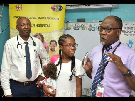 Senior Medical Officer, May Pen Hospital, Dr Bradley Edwards (right), thanks 10-year-old Canadian-Jamaican philanthropist Jazmin Headley for the donation of items for the setting up of the ‘Jazmin Corner’ on the Paediatric Ward. The space was opened on