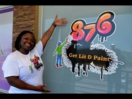 Jheanell Savage poses in front of her newest venture, 876 Get Lit & Paint.