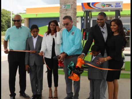Energy Minister Daryl Vaz gets some assistance as he cuts the ribbon to formally open the first Regency Petroleum Limited petrol service station at Paradise in Westmoreland on Wednesday. Joining him are (from left) Dr Andre Foote, chairman of Regency Petro