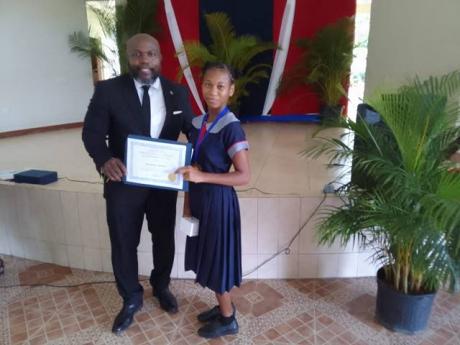 Shenniel Bowen of Lucea Primary School  is presented with her award by Joseph Campbell of the Campbell Family Foundation.