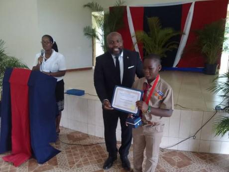 Keyjaun Matherson (right) of Esher Primary School, top boy performer at the school in the PEP exams, is presented with his awards by Joseph Campbell  of the Campbell Family Foundation. Principal of Esher Primary School Mrs A Wright is at the podium.