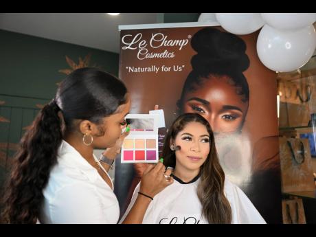 Make-up artist Afiya Birch-Gentles (left) expertly applies products from the Le Champ Cosmetics Vegan Blush/Highlighter Palette on Dayana Duval.