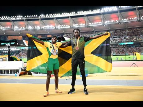 Wayne Pinnock (left) and Tajay Gayle celebrate after mining silver and bronze respectively in the men’s long jump final at the  2023 World Athletics Championships in Budapest, Hungary, yesterday. 
