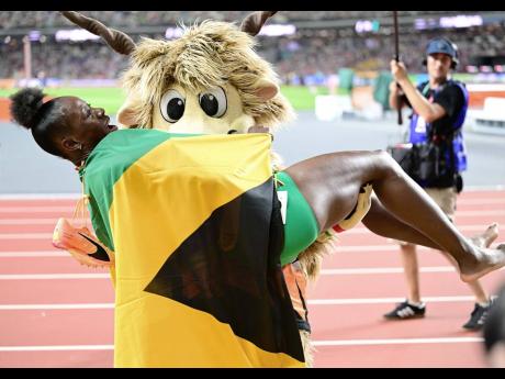 Youhoo, the Budapest 23 mascot, lifts Shericka Jackson as she celebrates her World Championship win in the women’s 200m final at the National Athletics Centre yesterday. Jackson won in a Championship 21.41 seconds. 