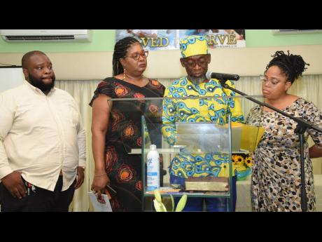 Jamaica Information Service senior reporter Garfield Angus (at podium) and staff members pay tribute to their former manager, Beverley Sinclair, at her thanksgiving service at the St Andrew Church of Christ on Thursday.
